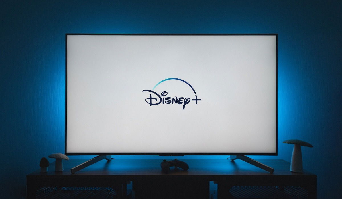 Large screen TV on top of a stand with blue light behind it in a dark room