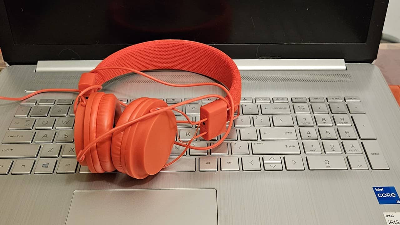 Red headphones sitting on a laptop keyboard.