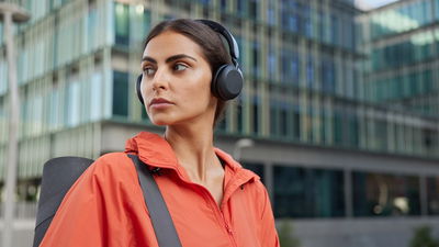 Sporty Active Woman Concentrated Into Distance With Thoughtful Expression Carries Rolled Fitness Mat Gets Ready For Training Poses Outdoors Against City Background. Athletic Female Exercises Regularly
