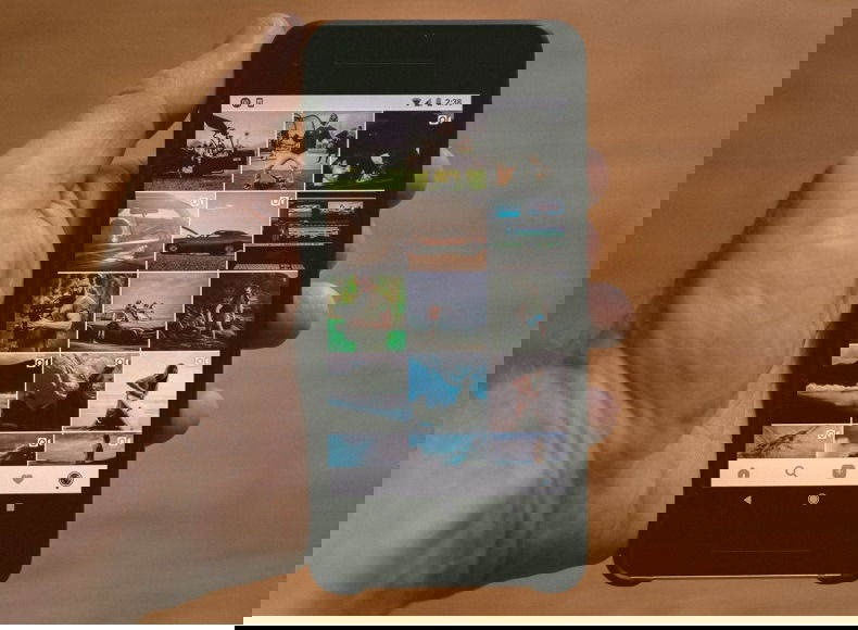 Hand holding a smartphone with photos on it.