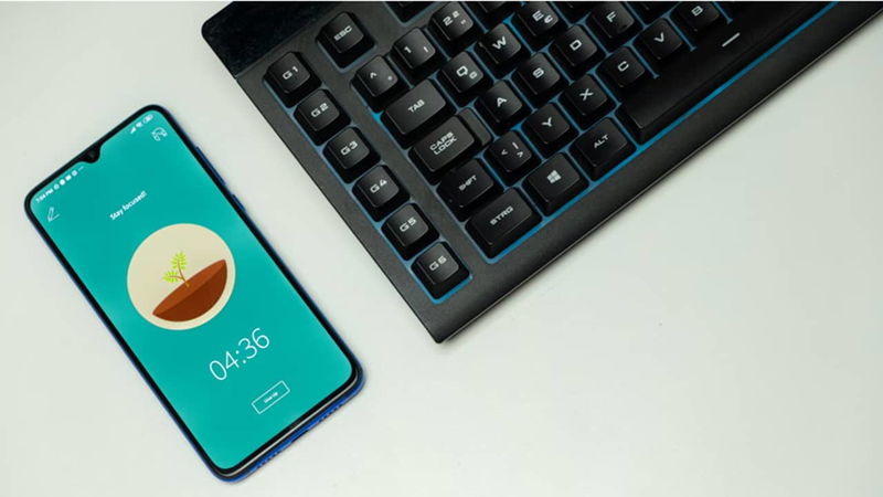 Phone sitting beside a keyboard.