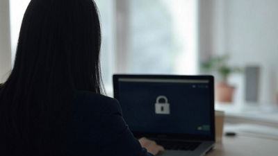 An image of a woman working in front of a laptop with the screen showing a lock icon.