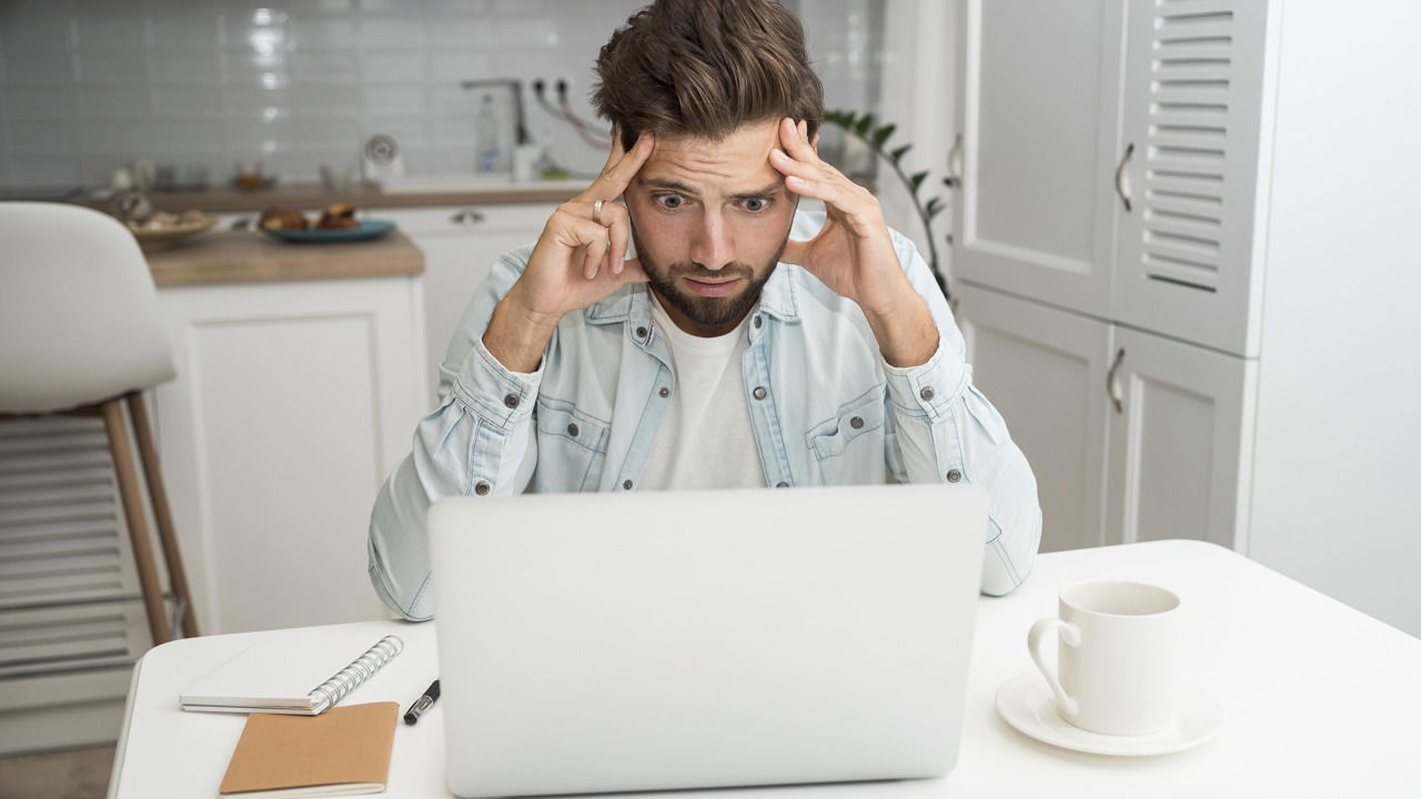 Man concernly looking at white laptop on table